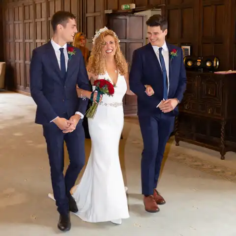 Wedding photo of the bride and her two sons escorting her down the aisle in the ceremony at Fanhams Hall, Ware, Hertfordshire.  – photography by Glen Smith