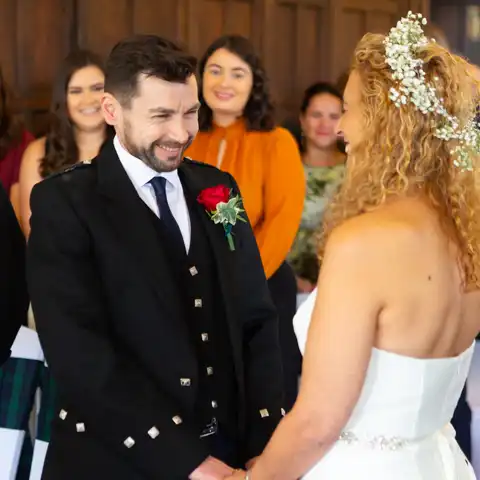Wedding photo of close up of the bride and groom exchanging vows and smiling at each other at Fanhams Hall, Ware, Hertfordshire.  – photography by Glen Smith