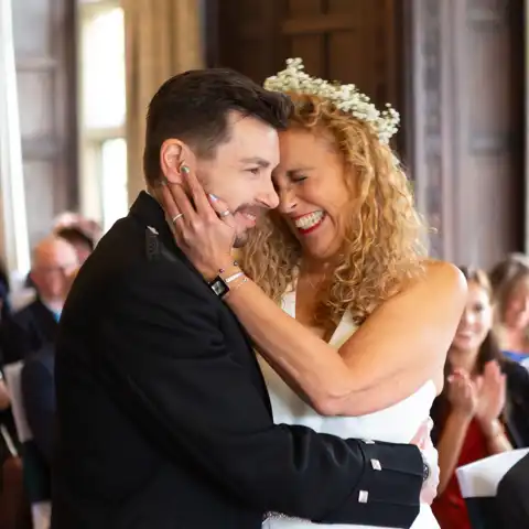 Wedding photo of the bride and groom looking very happy in the ceremony at Fanhams Hall, Ware, Hertfordshire.  – photography by Glen Smith