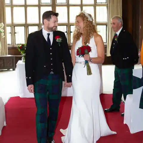 Wedding photo of the bride and groom walking down the aisle in the Long Gallery at Fanhams Hall, Ware, Hertfordshire.  – photography by Glen Smith