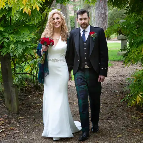 Wedding photo of the bride and groom walking through the beautiful grounds at Fanhams Hall, Ware, Hertfordshire.  – photography by Glen Smith