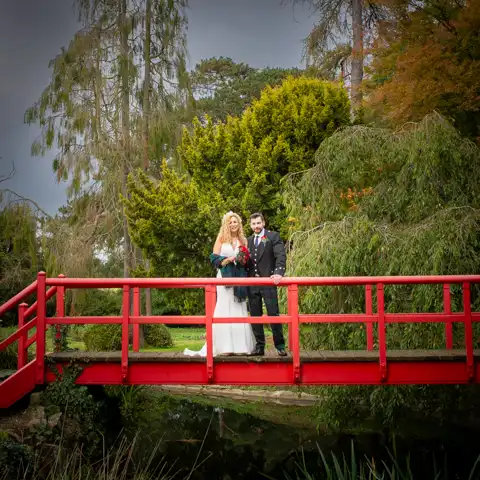 Wedding photo of the bride and groom on the red bridge at Fanhams Hall  at Fanhams Hall, Ware, Hertfordshire.  – photography by Glen Smith
