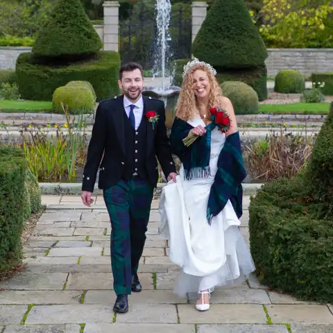 Wedding photo of the bride and groom walking in the grounds at Fanhams Hall, Ware, Hertfordshire.  – photography by Glen Smith