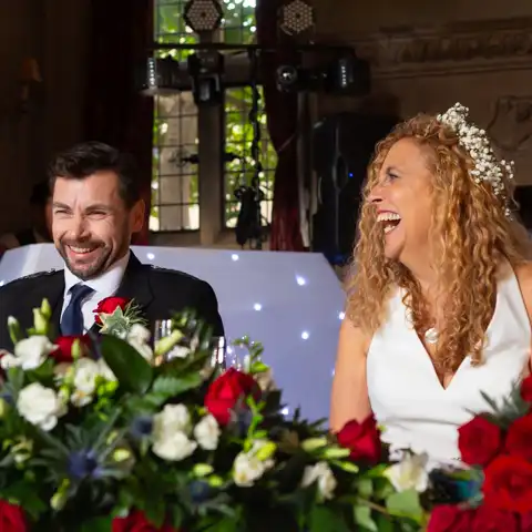 Wedding photo of the bride and groom laughing during the wedding speeches at Fanhams Hall, Ware, Hertfordshire.  – photography by Glen Smith