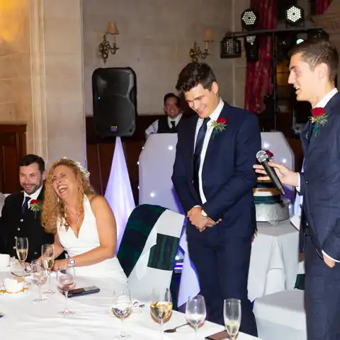 Wedding photo of the bride and groom laughing druing wedding speeches at Fanhams Hall, Ware, Hertfordshire.  – photography by Glen Smith