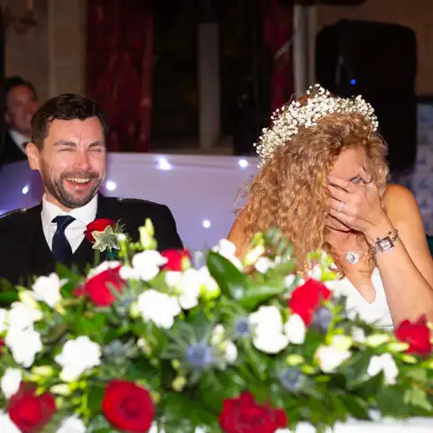 Wedding photo of the bride and groom laughing druing wedding speeches at Fanhams Hall, Ware, Hertfordshire.  – photography by Glen Smith