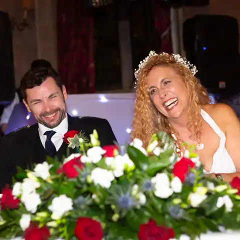 Wedding photo of the bride and groom laughing druing wedding speeches at Fanhams Hall, Ware, Hertfordshire.  – photography by Glen Smith