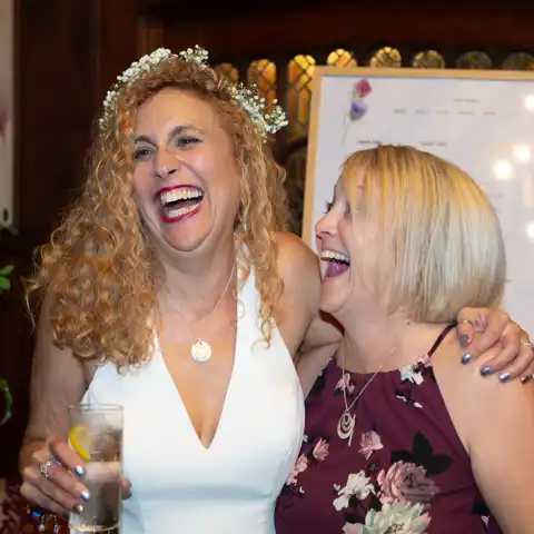 Wedding photo of the bride and guest laughing at Fanhams Hall, Ware, Hertfordshire.  – photography by Glen Smith